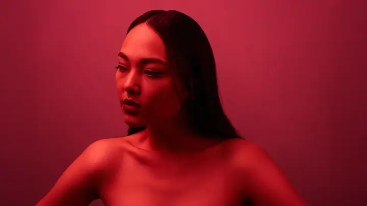 A gorgeous Asian descent woman in a glowing red light